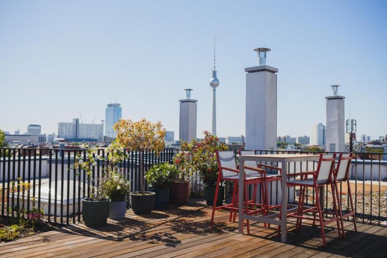 a table and chairs on a balcony with a view of the city at The Circus Apartments in Berlin 768x512