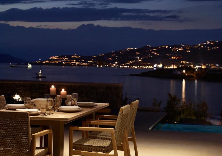 a table on a balcony with a view of the water at Bonzoe Suites Villas in Mikonos 1 768x540