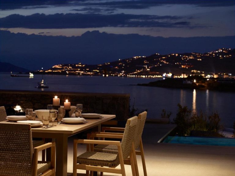 a table on a balcony with a view of the water at Bonzoe Suites Villas in Mikonos 768x575