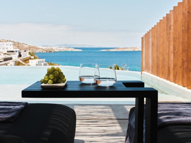 a table with two wine glasses and a bowl of grapes at BillCoo Mykonos The Leading Hotels of the World in Mikonos 768x576