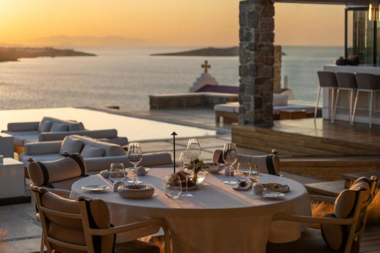 a table with wine glasses on top of a patio at BillCoo Mykonos The Leading Hotels of the World in Mikonos 768x512