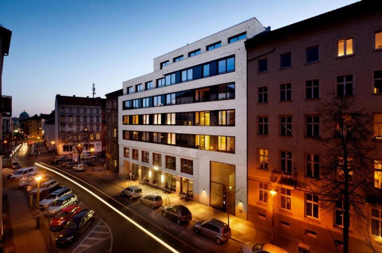 a tall building with cars parked in a parking lot at The Circus Apartments in Berlin 768x509