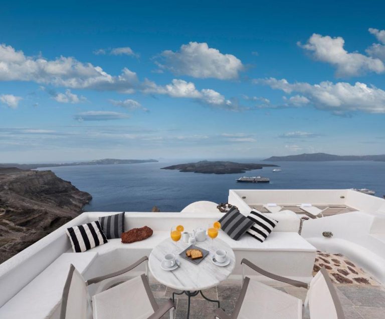 a white balcony with a table and chairs and the ocean at Aigialos Luxury Traditional Settlement in Fira 1 768x636