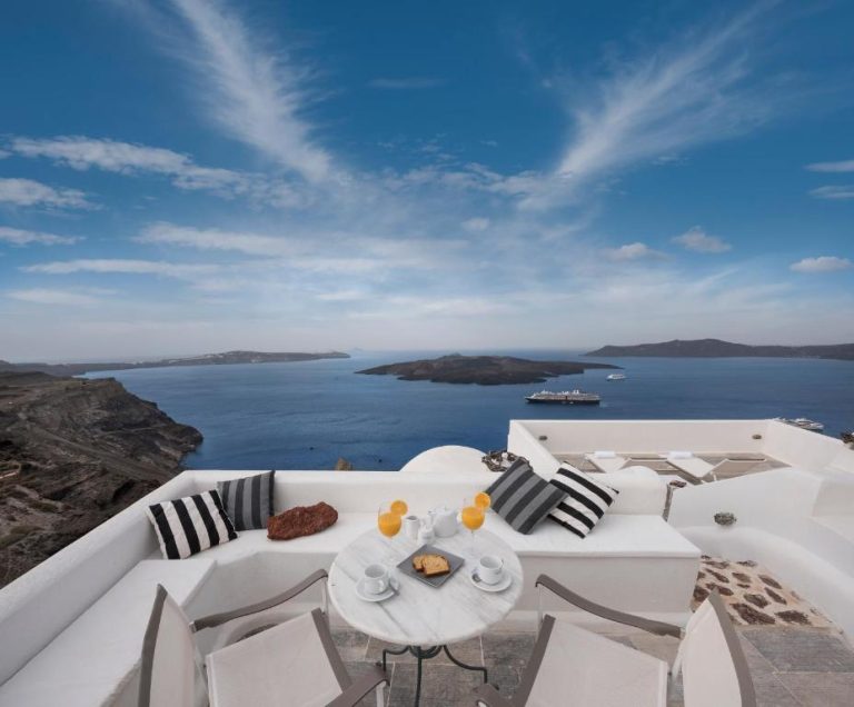 a white balcony with a table and chairs and the ocean at Aigialos Luxury Traditional Settlement in Fira 768x636