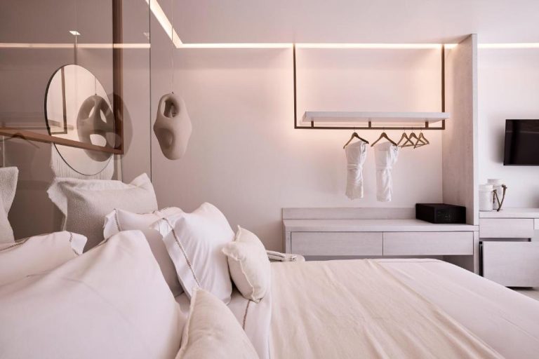 a white bedroom with a bed and a mirror at Ethereum Luxury Suites a member of Mykonos Highlights in Mikonos 768x512