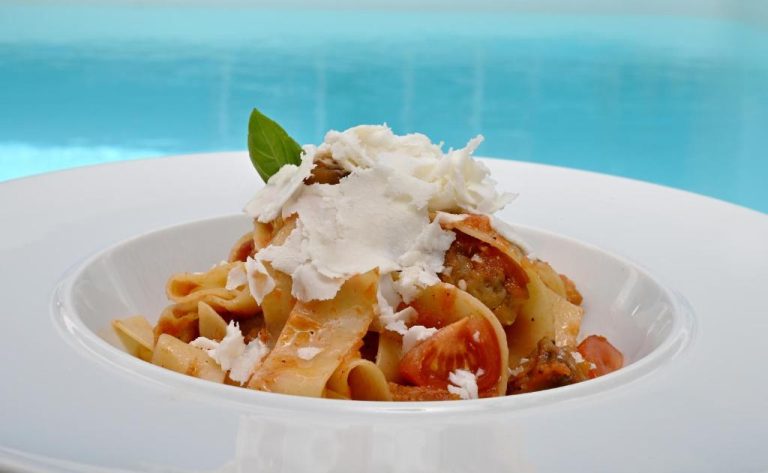 a white bowl of pasta with whipped cream and tomatoes at Aigialos Luxury Traditional Settlement in Fira 768x473