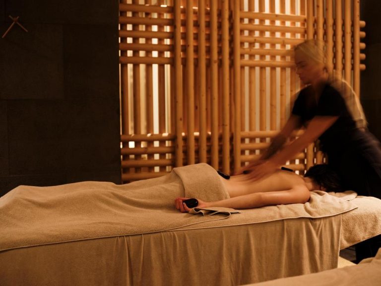 a woman is drying a man on a bed at BillCoo Mykonos The Leading Hotels of the World in Mikonos 768x576