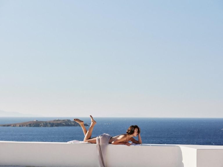 a woman is laying on a boat in the ocean at Boheme Mykonos Town Small Luxury Hotels of the World in Mikonos 768x576