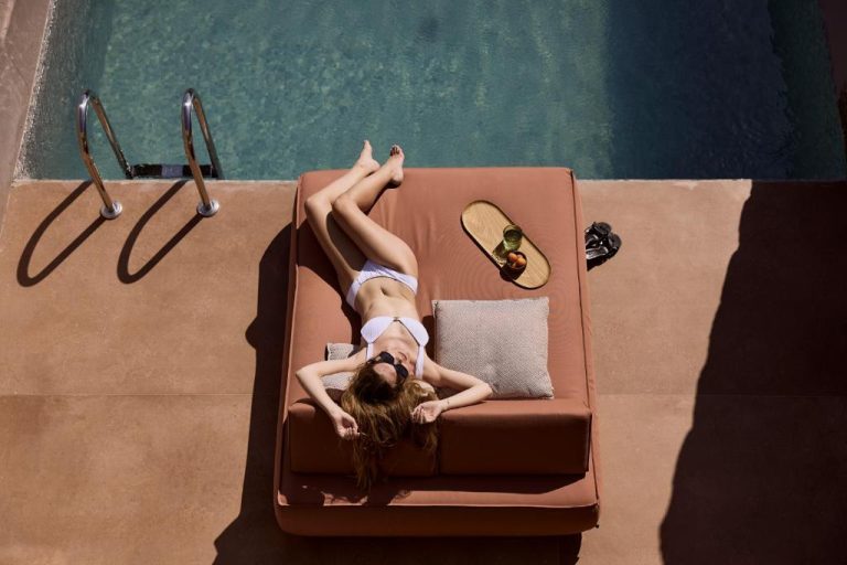 a woman laying on top of a suitcase at Ethereum Luxury Suites a member of Mykonos Highlights in Mikonos 768x512