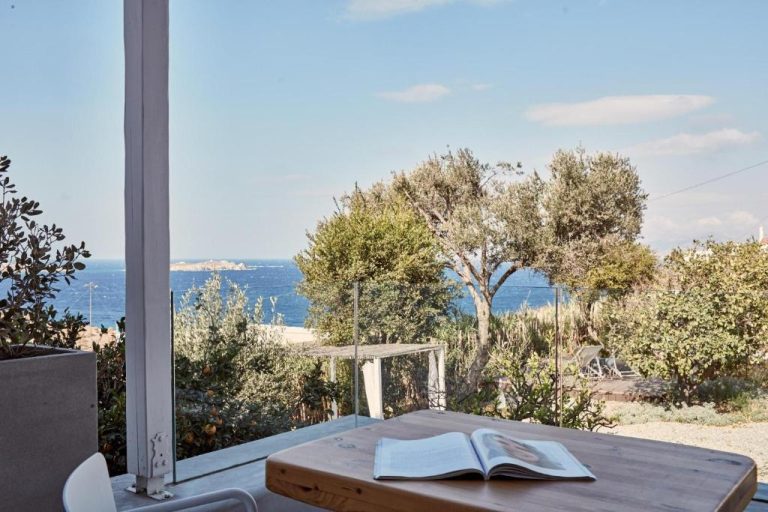 a wooden table with an open book on a balcony at Boheme Mykonos Town Small Luxury Hotels of the World in Mikonos 768x512