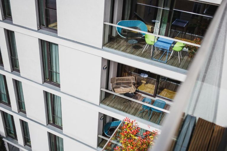 an apartment building with a balcony with chairs and tables at The Circus Apartments in Berlin 768x512