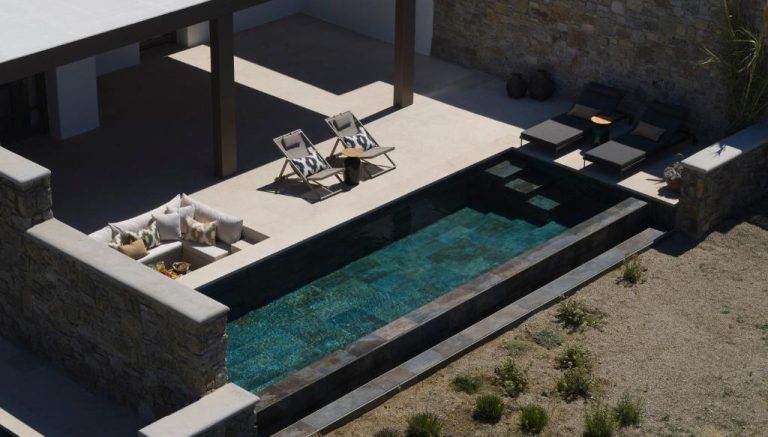 an overhead view of a swimming pool with two chairs and a table at Bonzoe Suites Villas in Mikonos 768x437