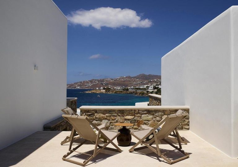 two chairs and a table on a balcony with a view of the ocean at Bonzoe Suites Villas in Mikonos 768x540