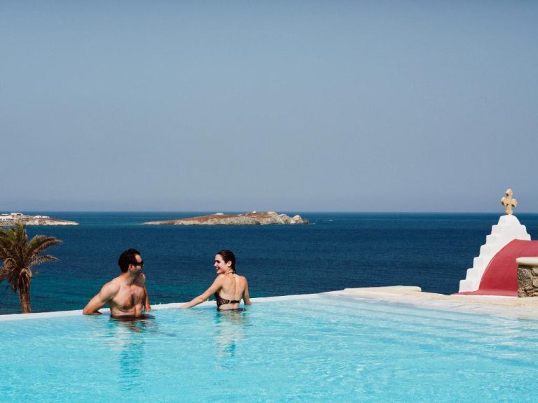 two people in a swimming pool next to the ocean at BillCoo Mykonos The Leading Hotels of the World in Mikonos 768x576