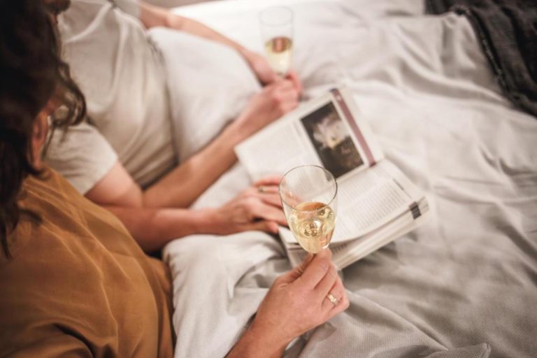 two people laying in bed reading a book and a glass of wine at The Circus Apartments in Berlin 768x512