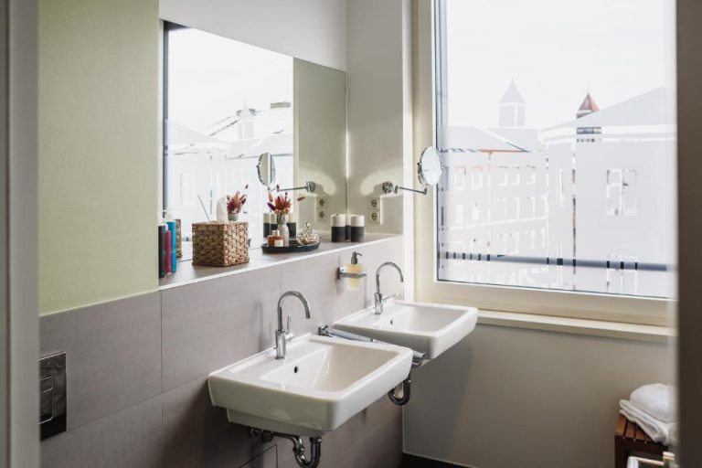 two sinks in a bathroom with a large window at The Circus Apartments in Berlin 768x512